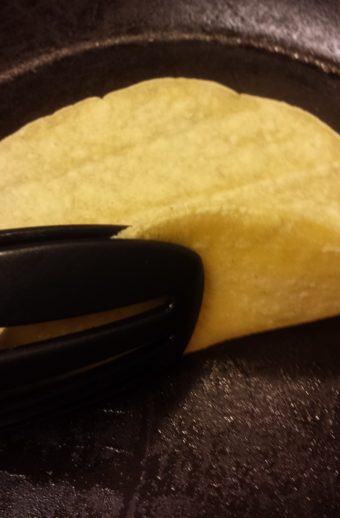 Warming a corn tortilla in a skillet before serving.