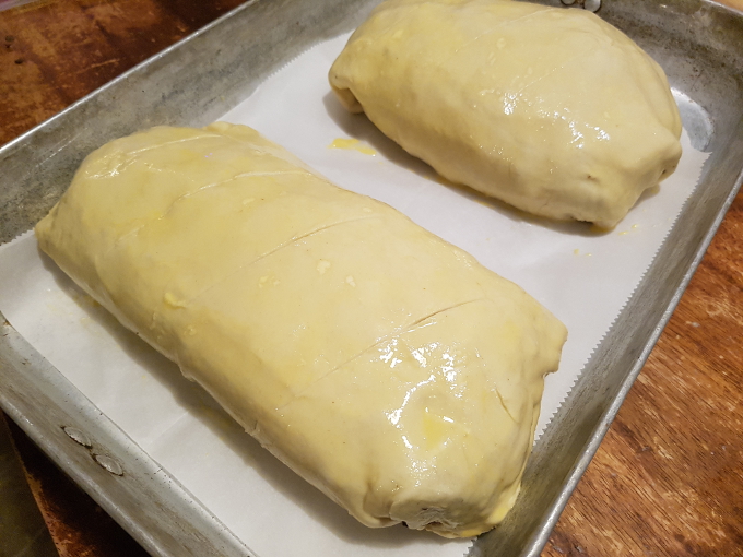 Beef Wellington coated in egg wash and scored