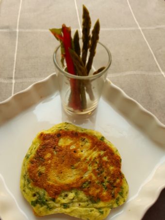 A green pancake with a side of pickled swiss chard stems and asparagus.