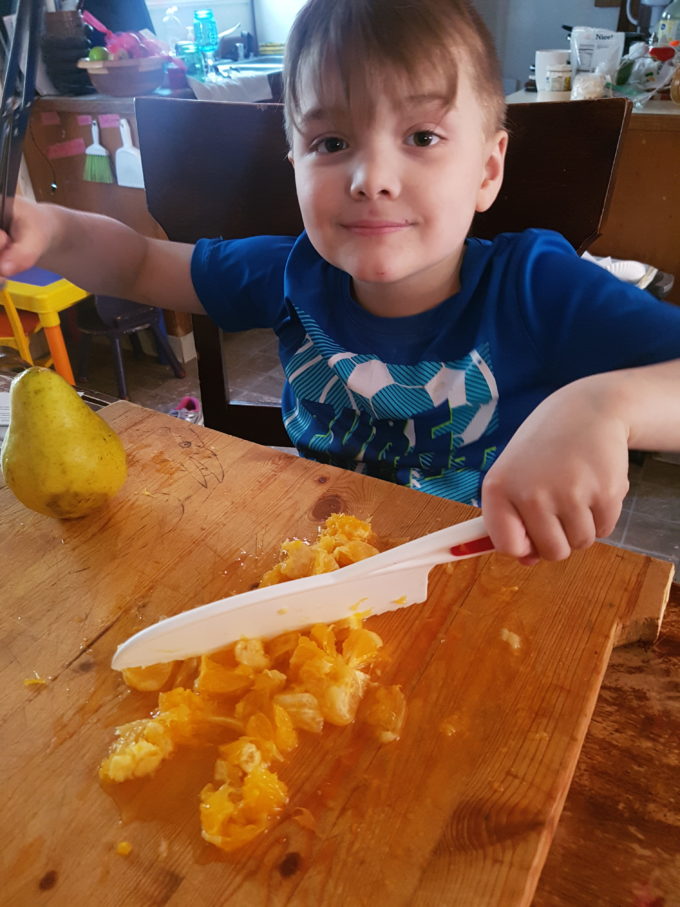 helping chop oranges with a plastic lettuce knife