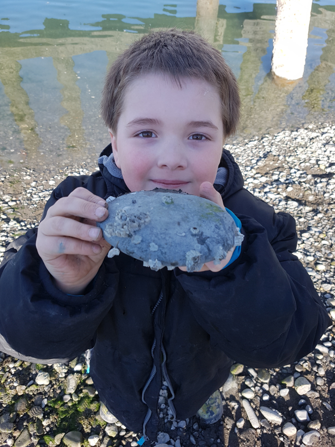 Nathan holding up a rock on the beach at the small boat harbor