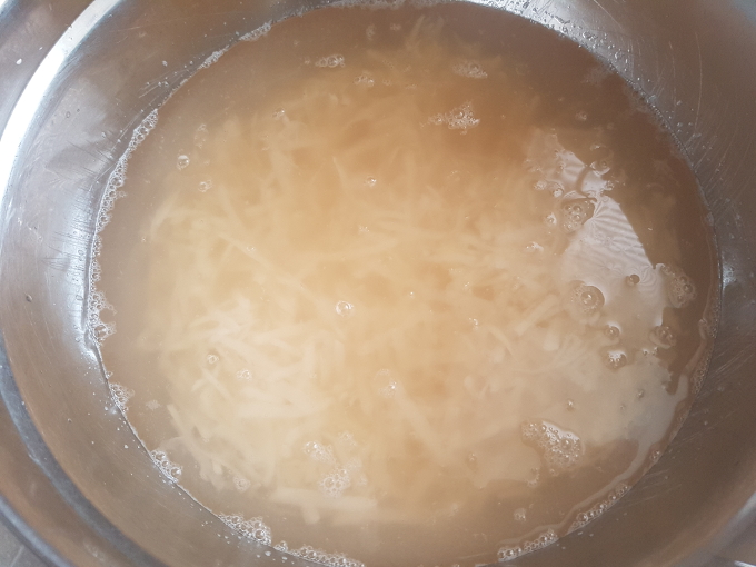 Hash browns soaking in water after they've been stirred