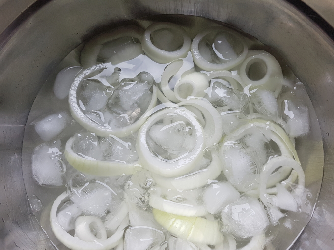 Onion rings being soaked in ice water